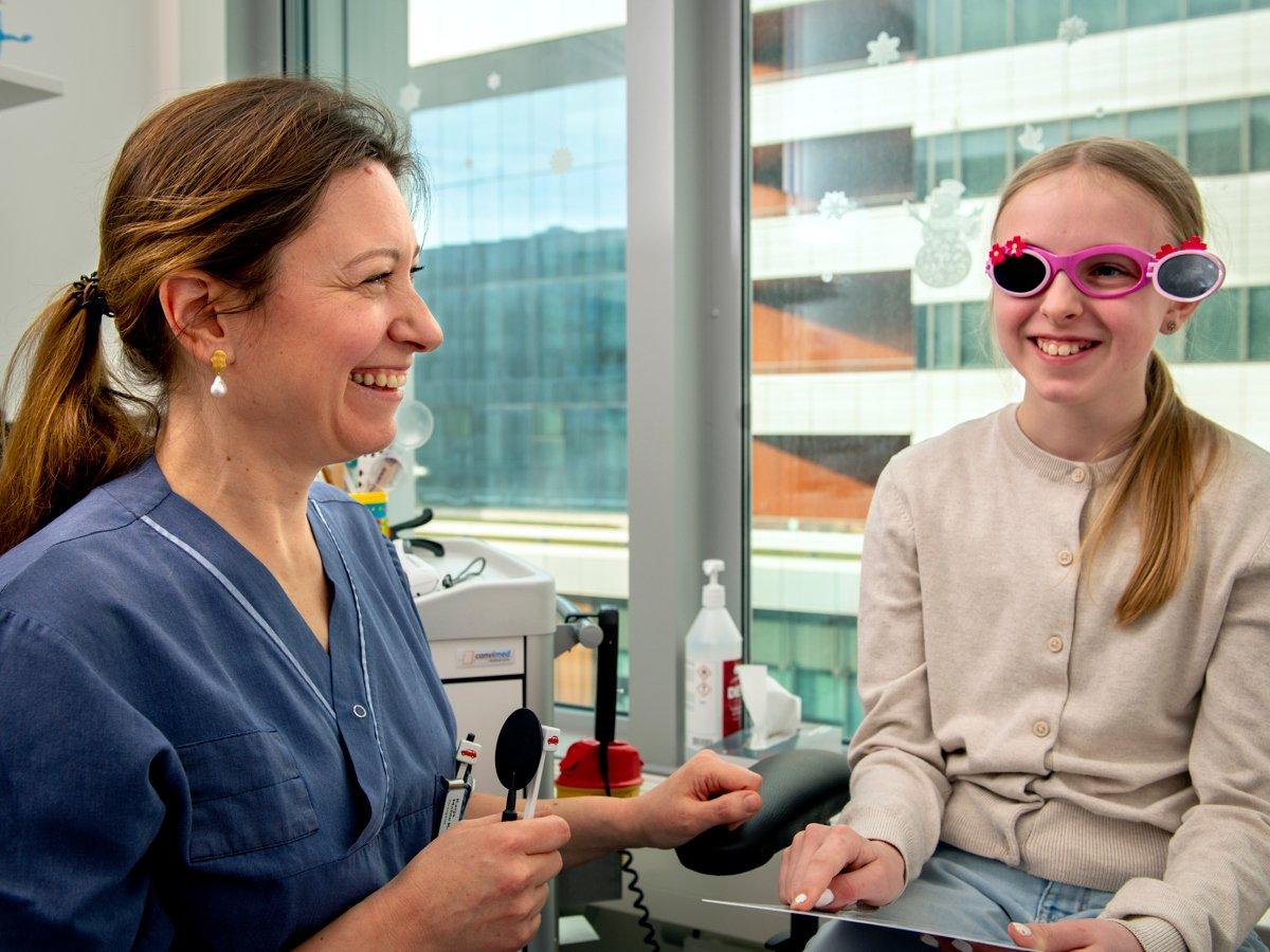 En kvinna i en sjukhuskläder med en patient. Patienten är ett barn som gör en synundersökning.