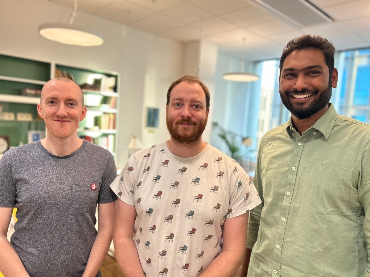 Tre killar står bredvid varandra och ler.