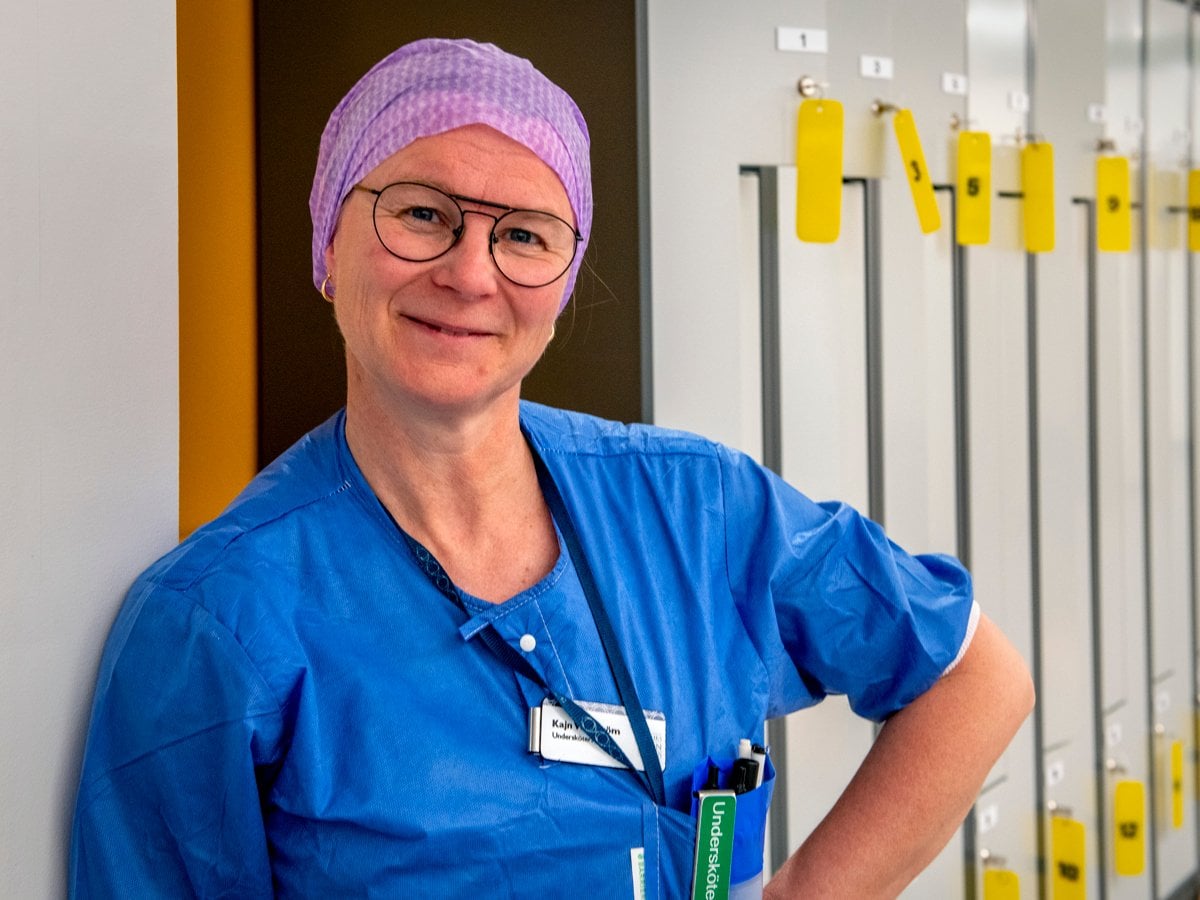 En kvinna i operationskläder står framför några skåp.