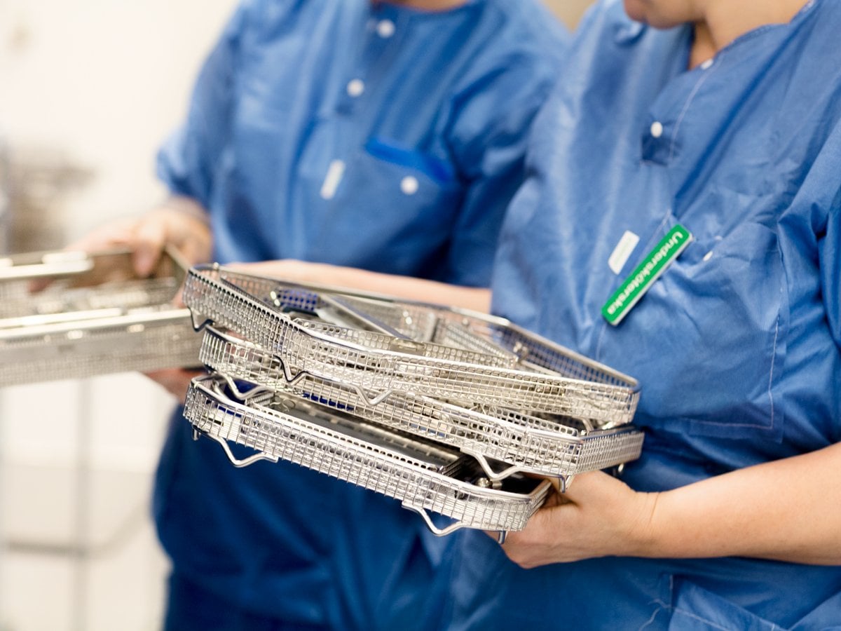 Två personer i operationskläder håller galler.