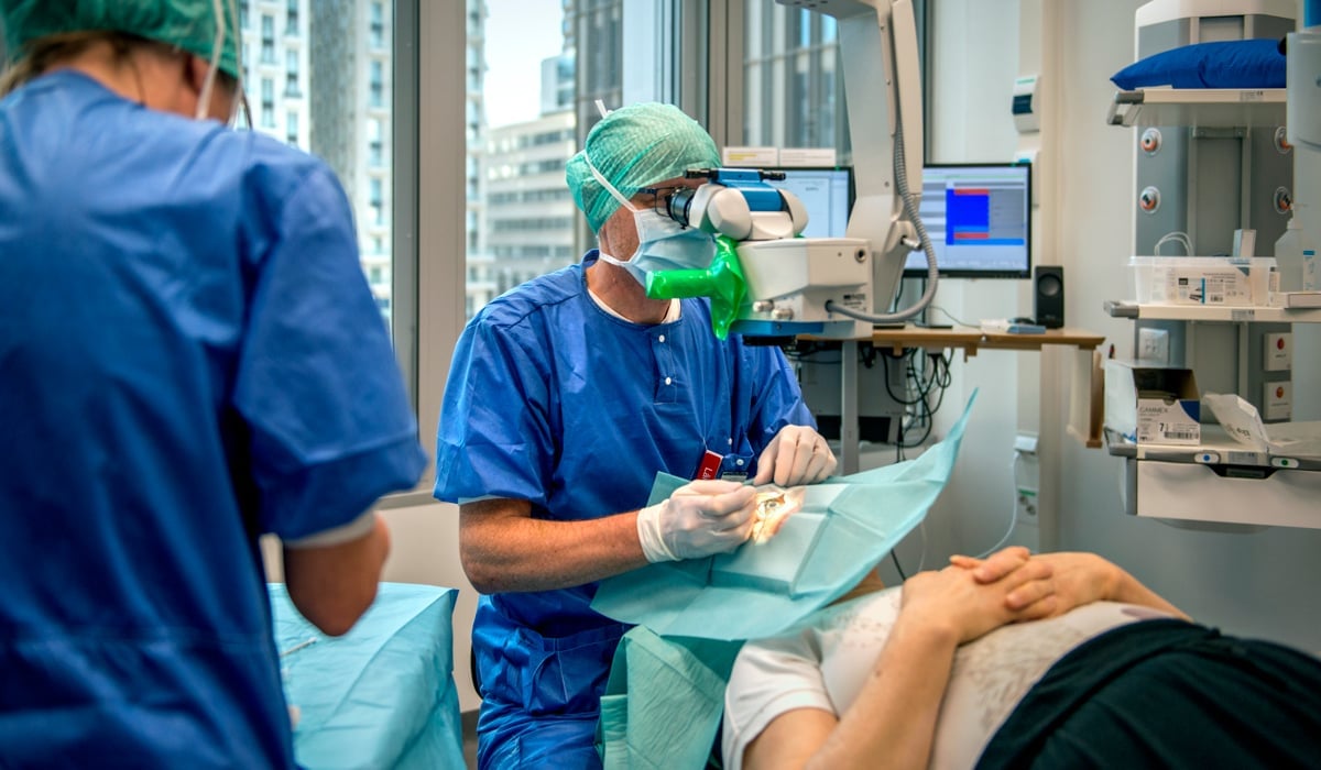 En person i operationskläder utför ett ingrepp.