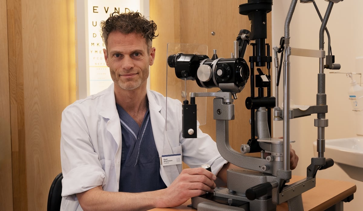 En läkare som sitter vid ett mikroskop.