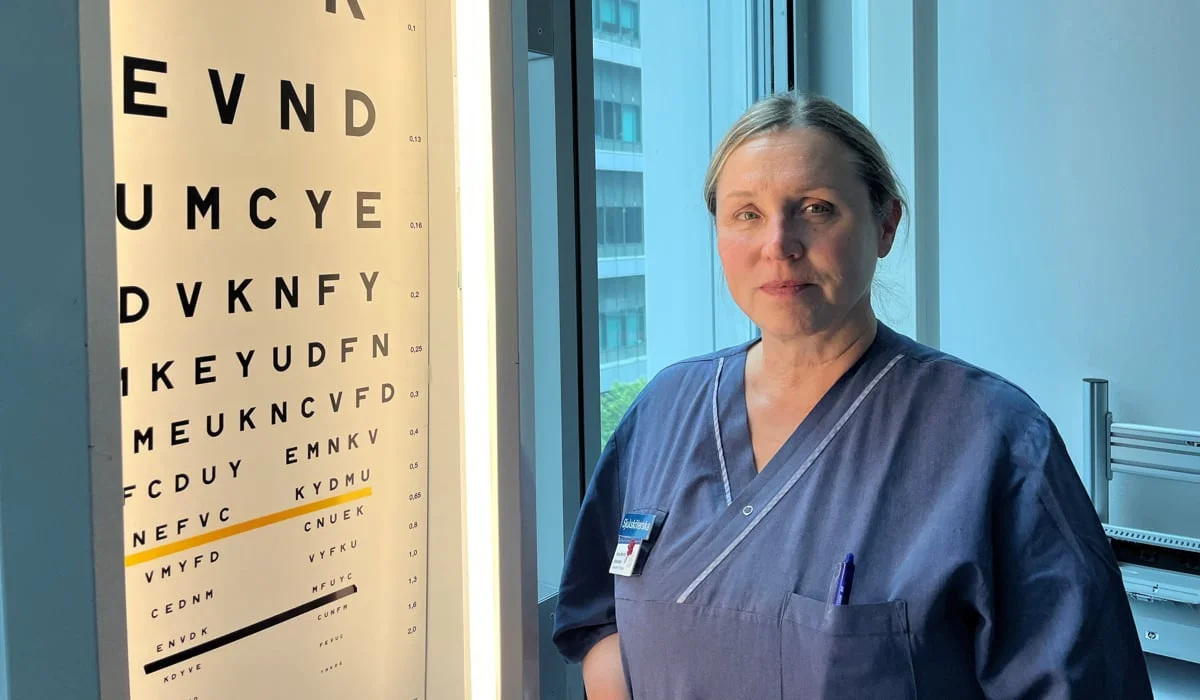 En kvinna i operationskläder står framför en syntavla.