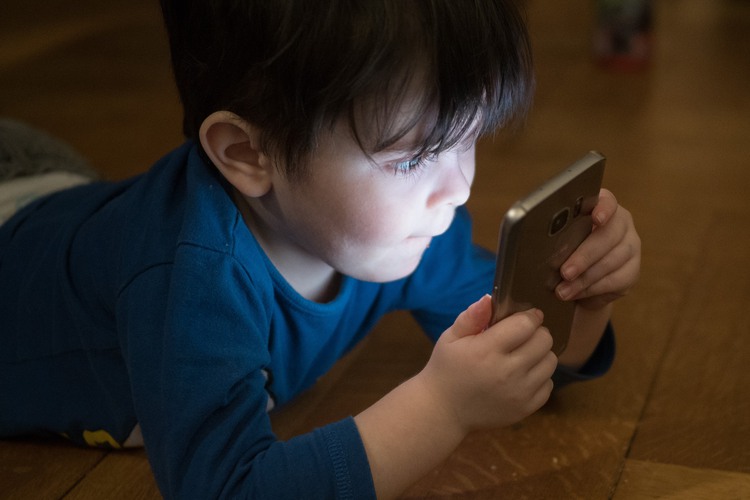 En liten pojke som använder en mobil.